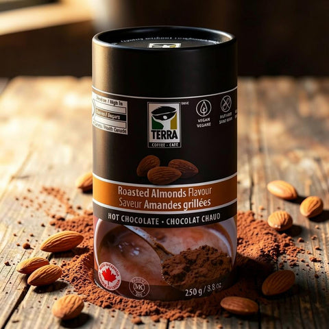 Bean Here Bean There Coffee & Cocoa Terra Roasted Almonds hot chocolate powder in a black canister on a wooden table.