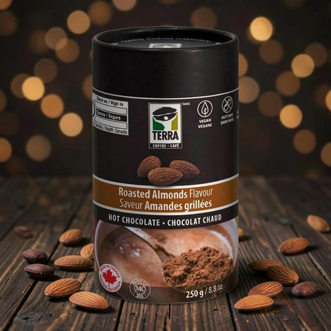 Bean Here Bean There Coffee & Cocoa Terra Roasted Almonds hot chocolate powder in a black canister on a wooden table.